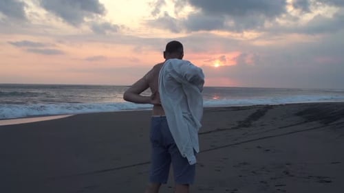 Man Putting on Shirt Standing on Beach During Sunset, Super