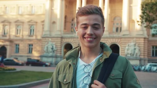 Portrait Young Man with Headphone Backpag Stand Look at Camera Smile Feel Happy on Street Outdoors