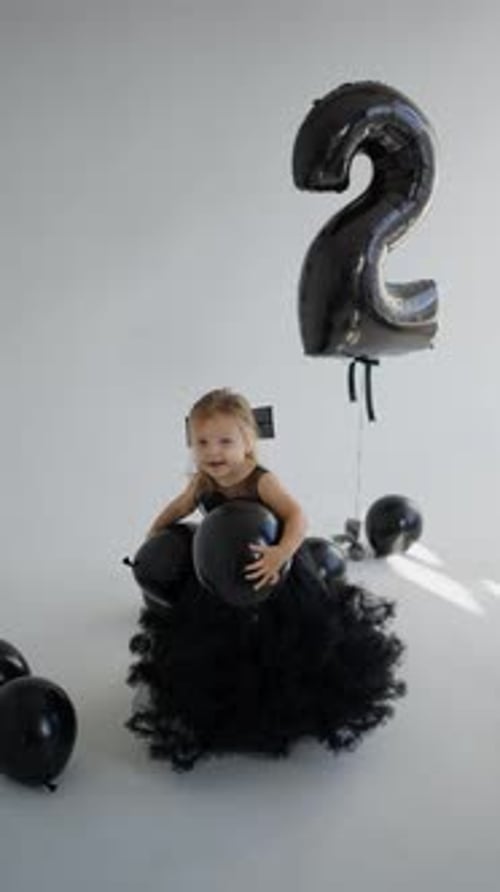 Little Girl Celebrates Second Birthday with Balloons