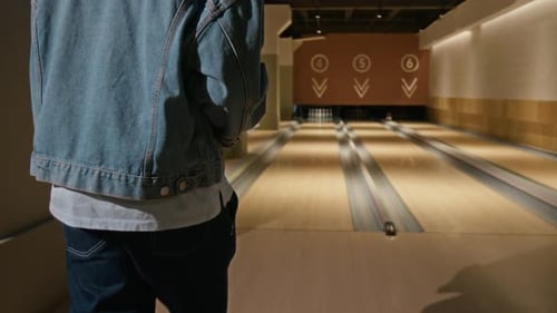 Schwarzer Mann wirft Bowlingkugel in der Bowlingbahn die Bahn hinunter