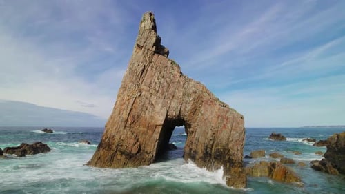 Sea arch in a wild pebble beach with sharp cliffs in the Cantabrian Sea in Asturias, Spain.