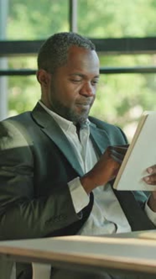 A Professional Man Engaged in Deep Reading and Thorough Analysis in a Modern Office Space