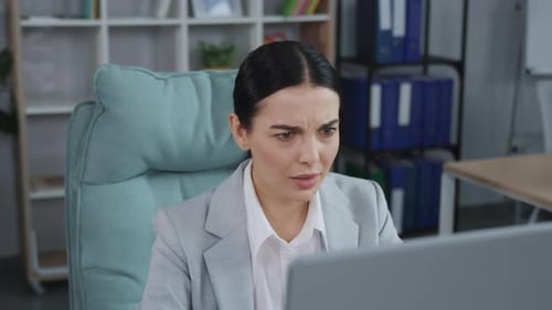 Businesswoman Looks at the Computer Screen with Fear of Terrible News While Sitting at Office