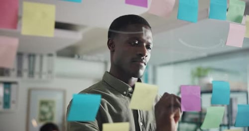 Man Writing Ideas on Glass Wall in Office