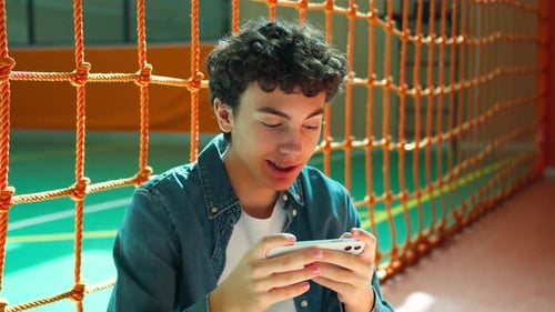 Teenage Boy Using Cellphone in Gymnasium