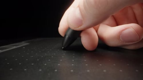 I write on a black graphics tablet. Dolly slider extreme close-up.