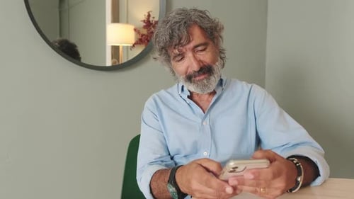 Man with Gray Hair Using Smartphone Indoors