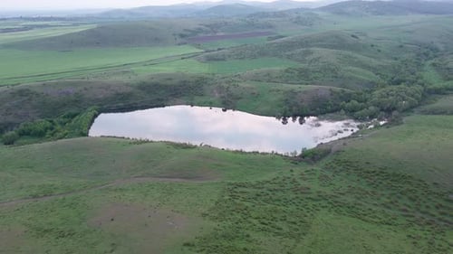 Lake with Clear Water is Located Between the Hills Greened with Grass in the Balkan Mountains Under