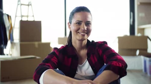 Smiling woman sits among moving boxes at home