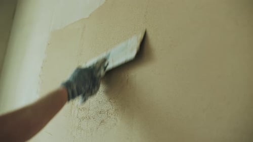 Hand Applying Plaster to Wall with Metal Tool