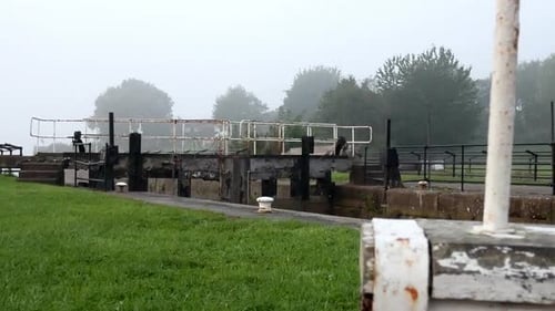 Industrial British canal lock gates towpath on English misty morning parallax right