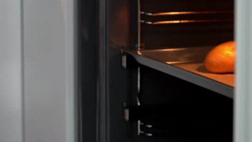 Hands Open Oven Door and Take Out Hot Baking Sheet with Baked French Baguette