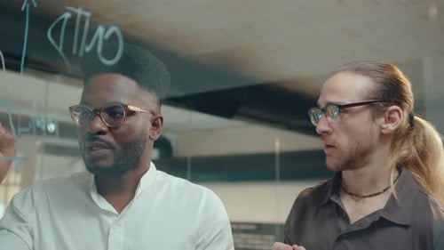 Men Drawing Financial Graph on Glass Wall and Talking in Office
