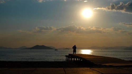 Alone Fisherman on Pier By Dusk Lake