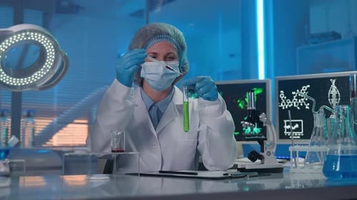 A Woman Scientist Pipettes a Red Drop of a Substance Into a Test Tube with a Green Liquid