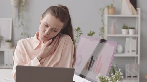 Woman Talks on Phone While Using Laptop