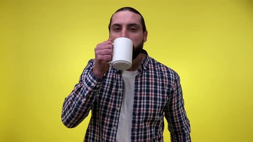 Adult Man Drinking From Mug on Yellow Background