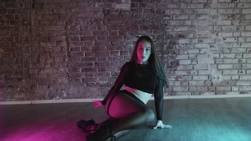 Stylish Woman Dances in a Studio with Brick Wall