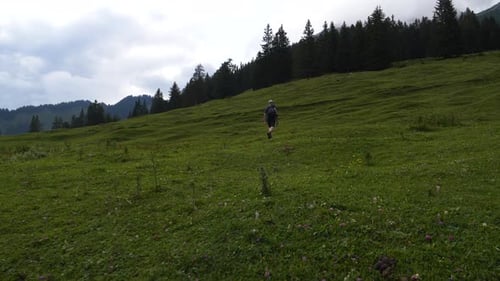 Man walking hiking up trail grass in the mountains Austrian Alps