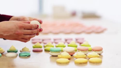 Chef sandwiching macarons with cream together at a french pastry shop