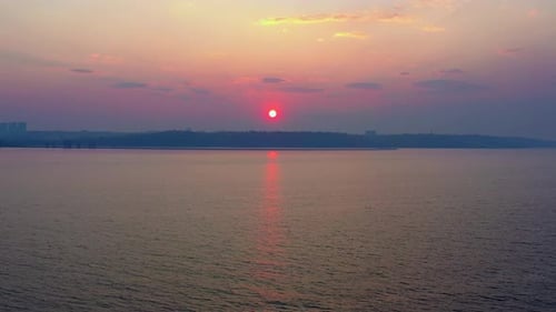 Sunset By the Lake at Golden Hour with Orange Sky and City Skyline on the Hill
