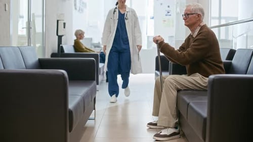 Aged Man Getting Support from Female Doctor in Hall of Clinic
