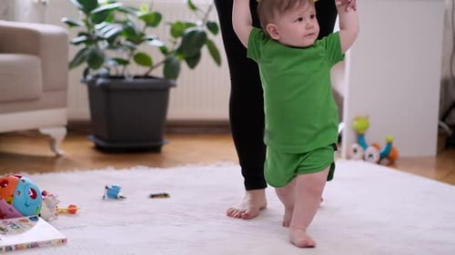 Infant Taking First Steps with Adult Guidance