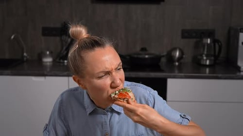 A Woman is Sitting at a Wooden Table in a Modern Kitchen Eating a Homemade Meal On the Plate are