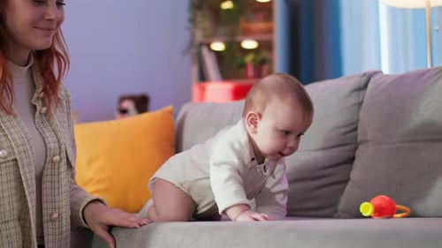 Adorable Baby Crawling on Sofa with Mother Nearby
