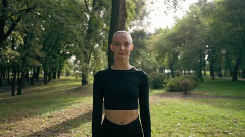 portrait of a young beautiful girl in sportswear in a city park before the start of sports training