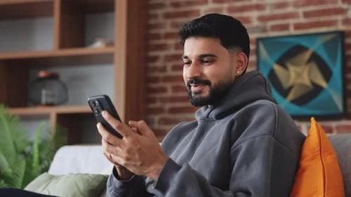 Young Adult Using Smartphone Sitting on Couch