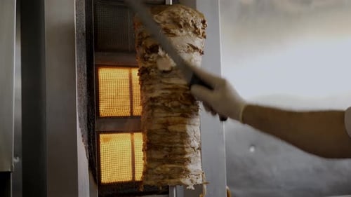 Chef Cutting Slices Out Of Big Chicken Shawarma Skewer Hanged On Grill