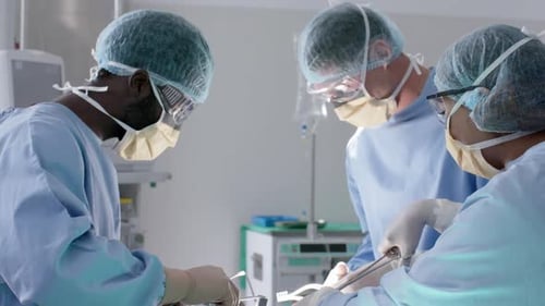 Focused diverse male and female surgeons with face masks during surgery in slow motion, unaltered