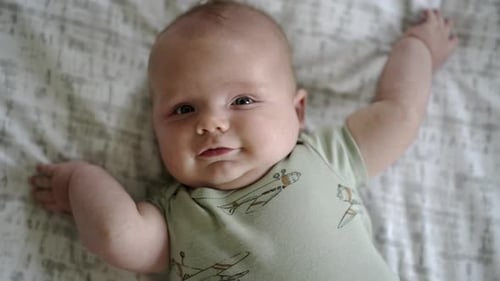 Baby Caucasian boy playing with a colorful toy on a white play mat
