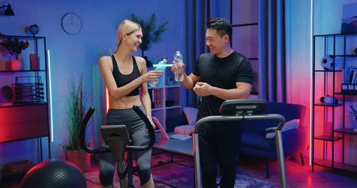 Couple Exercising and Drinking Water in Home Gym