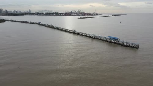 Vista aérea do cais que se estende da terra até a água no vasto oceano sem fim.