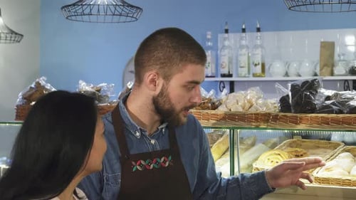 Friendly Male Baker Assisting Mature Female Customer in a Cozy Bakery