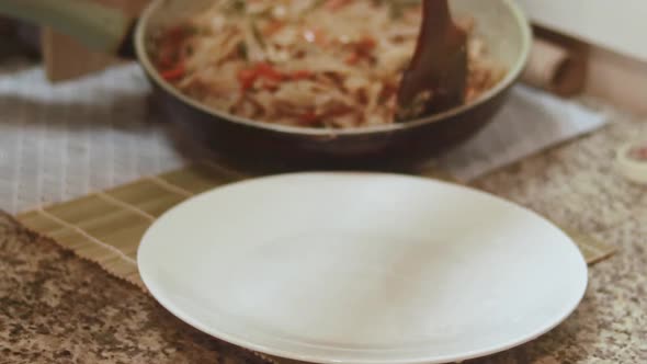 Serving newly cooked stir-fried vegetable rice noodles into a plate ...