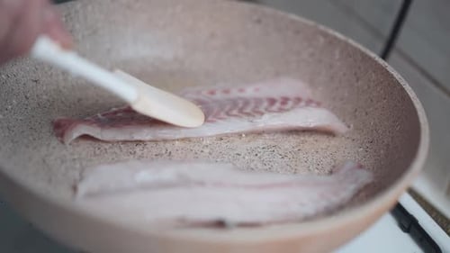 Woman pirien fish in a pan at home. close-up. homemade fish grill