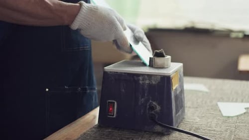 Man Grinding Glass Edge with Machine in Workshop