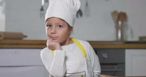 Smiling Child in Chef Hat in Kitchen