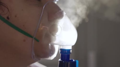 Gros plan d'une fille faisant une inhalation avec un nébuliseur à la maison