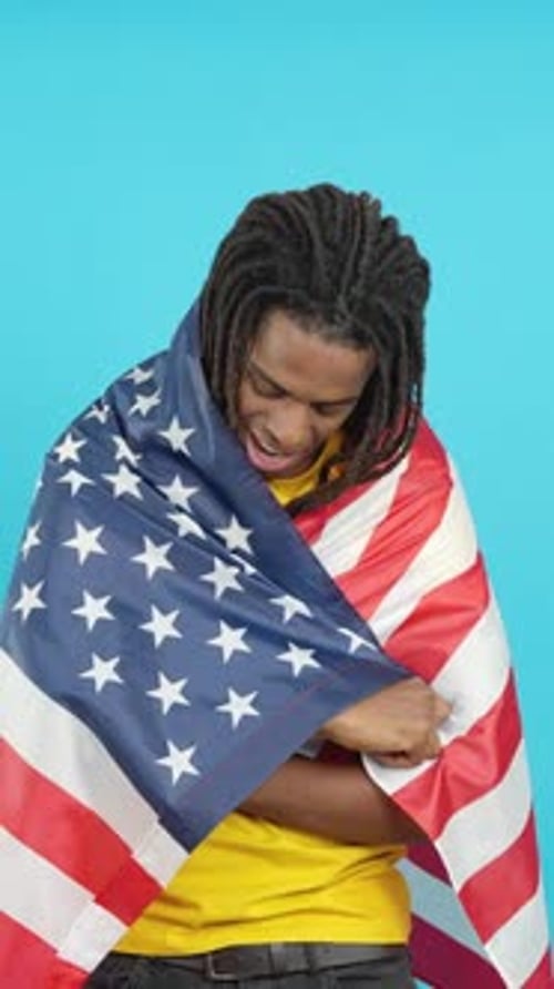 Man Smiling Wrapped in American Flag on Blue