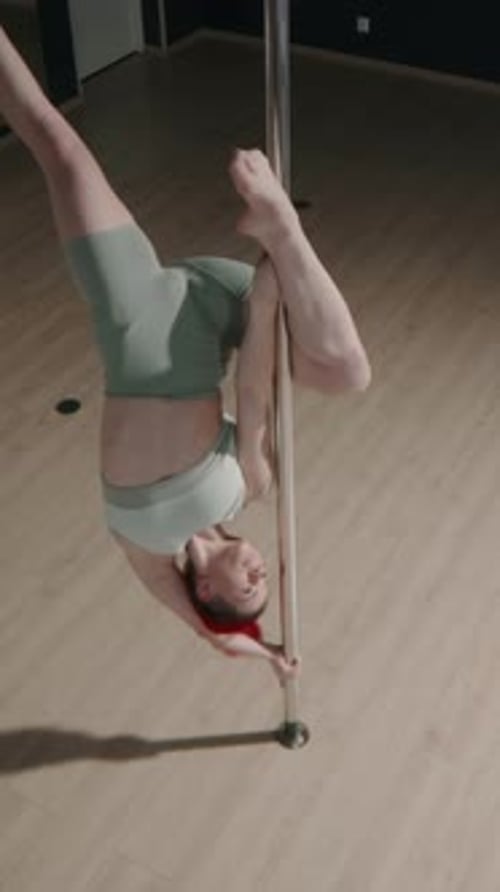 Vertical of Graceful Woman Pole Dancing in Studio