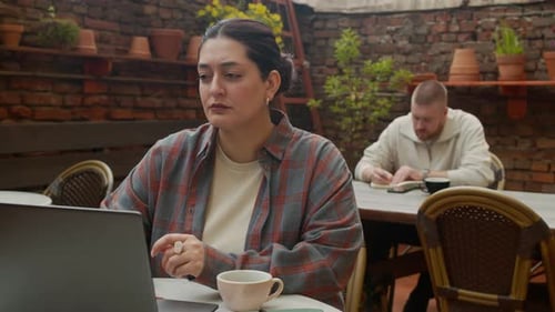 Female Freelancer Working on Laptop while Man Taking Notes in Background