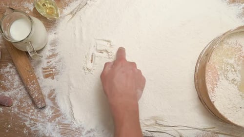 Hand Writing Food in Flour on Table