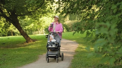 Mom and Child Outdoors Happy Mother Drinks Coffee While Walking in the Summer Park with Her Young