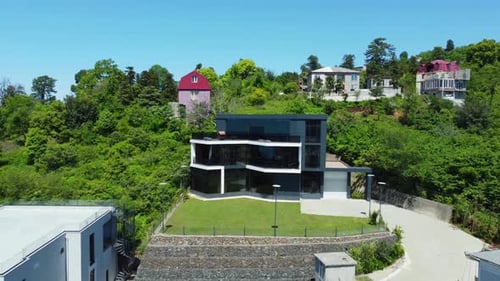 Modern glass house standing out in green forested neighborhood