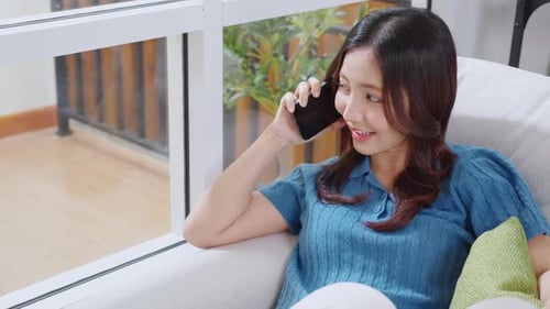 Happy Woman Talking on Phone While Relaxing at Home