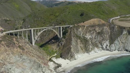 Kaliforniens berühmte Bixby Creek Bridge, Wellen, die unten am Strand krachen, Berge im Hintergrund